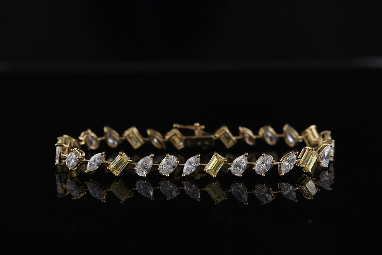 Luxurious diamond and gold bracelet reflecting on a black surface, showcasing elegance and sophistication.